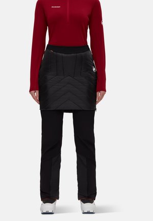 Red long-sleeve top with a quarter zip, paired with a black quilted skirt featuring a chevron pattern and a black pant base with textured accents.