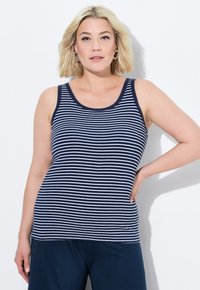 Canottiera a righe blu navy e bianca con scollatura a barco, realizzata in materiale a costine. Abbinata a pantaloni blu navy. Texture liscia, design casual.