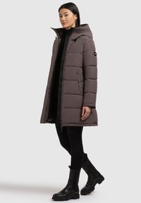 Puffer coat in dark gray, featuring a hood, zip closure, and side pockets. Made from smooth fabric with a quilted pattern. Black accents visible.