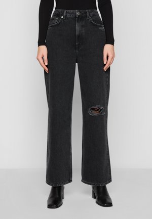 Svarte høy midje vide jeans i denim stoff, med ripskjøtt detalj og sidelommer. Parret med svarte hæl støvler.