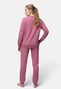 Completo in cotone rosa, composto da felpa e pantaloni, con maniche lunghe e polsini elasticizzati, dal taglio rilassato e design minimalista.