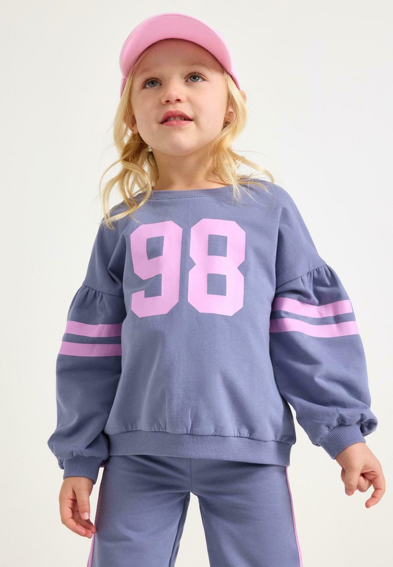 Paarse trui met opgeblazen mouwen en roze gestreepte accenten, met een gedurfde "98" print op de voorkant. Zachte katoenstof.