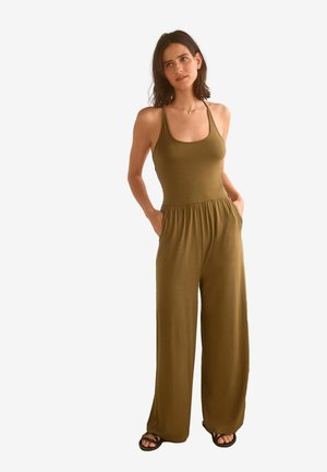 Olivengrön jumpsuit med en figurnära överdel, vid ben design och fickor. Tillverkad av mjukt material med en slät yta och enkla remmar.