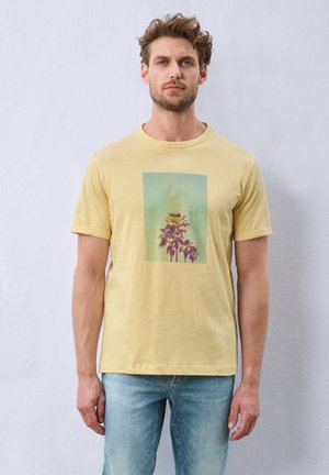 Korte mouwen gele t-shirt met een groene rechthoekige afbeelding van palmbomen, tegen een gradient achtergrond. Zachte textuur, casual pasvorm.