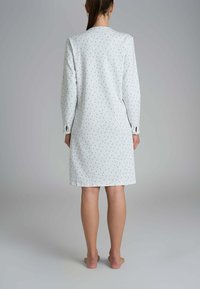 Vestito da notte a maniche lunghe con motivo floreale in bianco e dettagli azzurri. Presenta una linea dritta e maniche con bottoni. Tessuto morbido.
