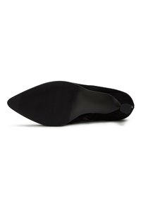 Zapato de tacón alto negro con puntera afilada y parte superior de ante elegante. Suela de goma texturizada para agarre, con un pequeño acento circular cerca del tacón.