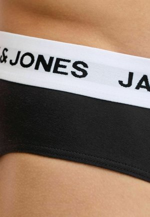 Crni donji rublje s bijelim pojasom na kojem se nalazi djelomično vidljiv podebljani crni tekst "JACK & JONES", nošeno na bokovima osobe.