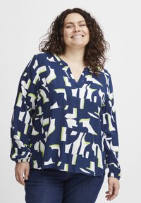 Blusa blu navy con motivi astratti bianchi e verdi, scollo a v, maniche lunghe con polsini elasticizzati, realizzata in tessuto leggero e liscio.