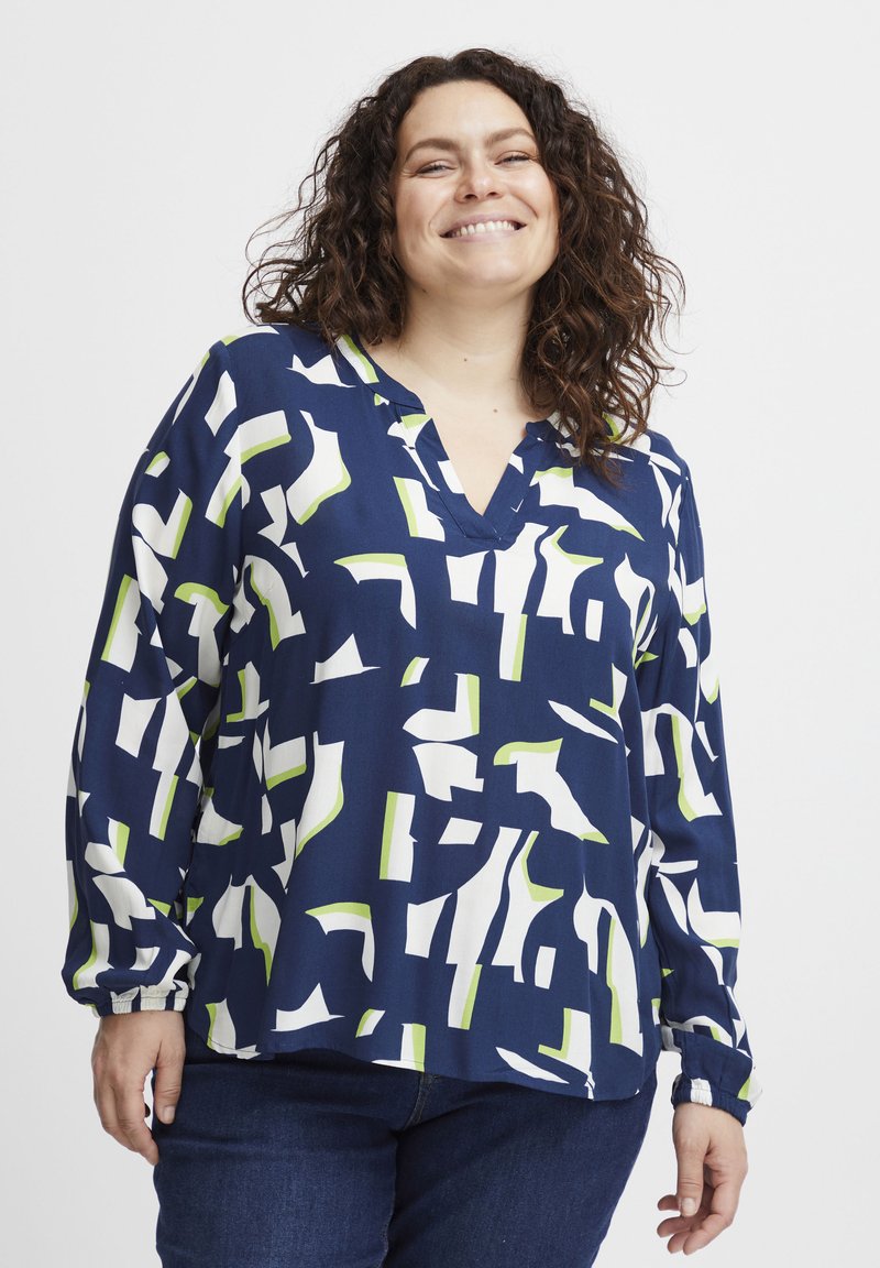 Blusa blu navy con motivi astratti bianchi e verdi, scollo a v, maniche lunghe con polsini elasticizzati, realizzata in tessuto leggero e liscio.