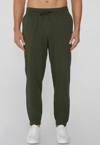 Grüne Jogginghose aus weichem Stoff, mit elastischem Bund, verstellbarem Kordelzug und schmal zulaufenden Bündchen. Tragen Sie dazu weiße Sneakers.