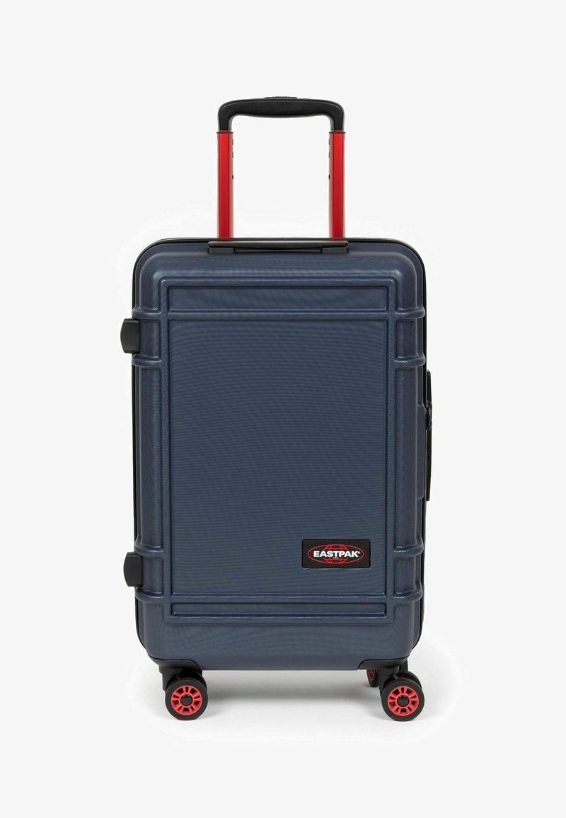 Námořnický tvrdý kufr s červenými akcenty, vysouvací rukojeť, čtyři černá kolečka, texturovaný povrch a viditelné logo značky na přední straně.