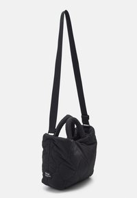 Sac bandoulière matelassé noir avec une texture douce, une anse courbée et une bandoulière réglable. Il présente une forme rectangulaire avec un patch logo.