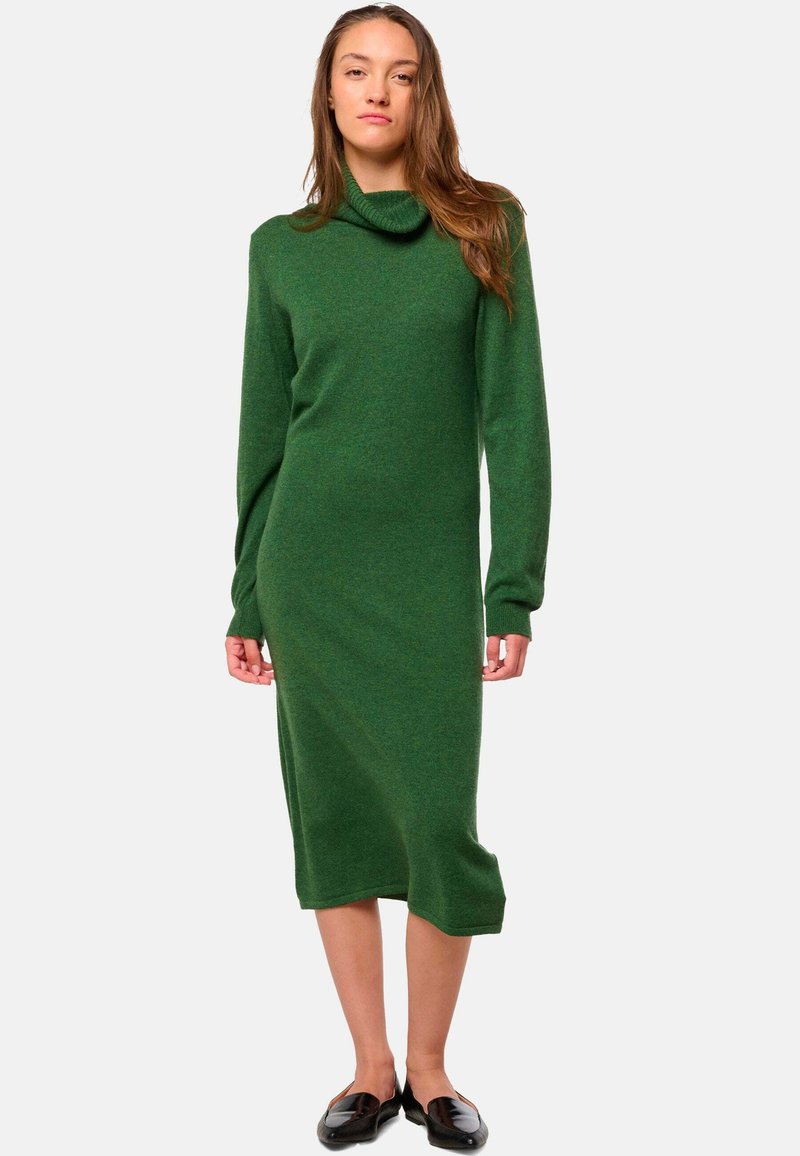 Langärmliges grünes Strickkleid mit hohem Kragen, schmalem Schnitt und gerippten Bündchen. Glatte Textur und Länge bis zur Mitte der Waden.