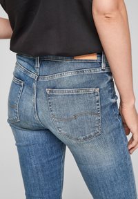 Hubené džíny v středně modrém denimu, s klasickým designem zadních kapes se švy a koženou etiketou v pase.