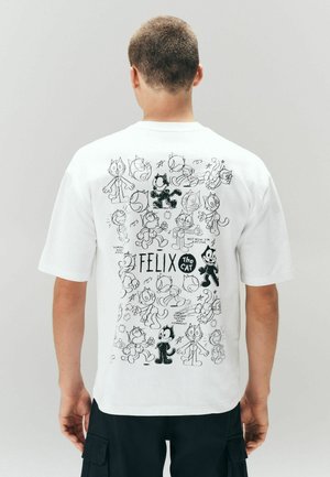Osoba nosząca białą koszulkę z różnymi czarno-białymi szkicami kreskówki Felix the Cat i napisem na plecach.
