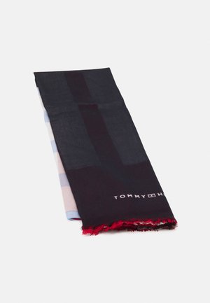 Opgevouwen zwarte en donkerblauwe Tommy Hilfiger sjaal met rode franjes aan de randen op een effen lichte achtergrond.