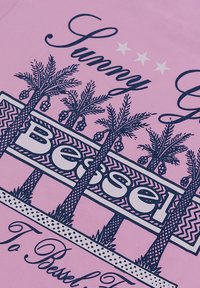 Camiseta de algodón de color rosa claro con un diseño gráfico en azul marino que incluye palmeras, el texto "Sunny" y "Bessel", y acentos de estrellas.