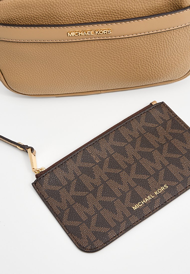 Bolso cruzado de cuero marrón con herrajes dorados y logotipo embosado; tarjetero oscuro con patrón marrón superpuesto y un acento de logotipo en tono marrón claro.