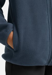Giacca in pile blu navy con superficie testurizzata, dotata di zip completa, tasche laterali e polsini elasticizzati.