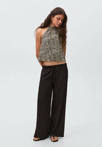 Floral-patterned halter top in muted colors, paired with loose black pants, featuring a drawstring waist. Soft fabric with natural texture.