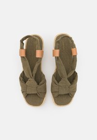 Olive green espadrille sandals with knotted fabric upper, tan leather accents, and jute sole. Soft texture with a casual design.