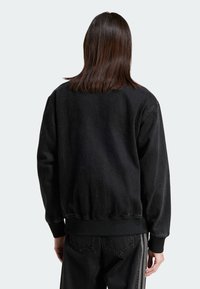 Svart sweatshirt med strukturerad textil, ribbade ärmslut och nederkant, med en avslappnad passform och en klassisk crew neck-design.