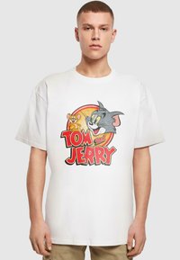 Weißes Baumwoll-T-Shirt mit einem farbenfrohen Grafikdesign von Tom und Jerry, mit kräftigen roten und gelben Buchstaben in einem lässigen Schnitt.