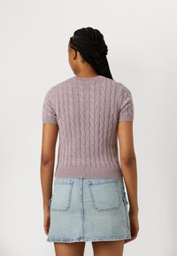 Kortärmad lavendelfärgad kabelstickad tröja med ribbad nederdel, ihop med en ljus denim minikjol med bakfickor.
