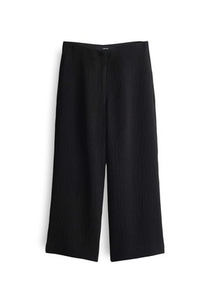 Pantalons larges noirs en tissu texturé avec une taille haute et des ouvertures de jambe bien finies, présentant un design minimaliste.
