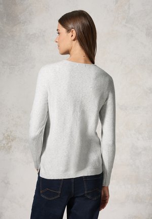 Pull long à manches longues gris clair avec un col rond et un ourlet côtelé. Fabriqué dans un tissu doux avec une texture lisse, porté avec un jean sombre.