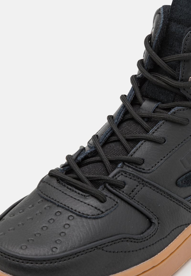 Sneaker alta in pelle nera con punta tonda, superficie texturizzata e perforazioni circolari. Dotata di lacci neri e suola in gomma color gomma.