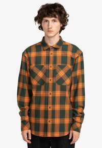 Grøn- og orangeternet skjorte i button-up stil, med to brystlommer, lange ærmer og krave. Tekstureret stof.