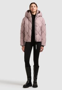 Polstret, lys mauve jakke med diamant-quilt mønster og aftagelig hætte. Sammen med sorte leggings og knæhøje sorte støvler.