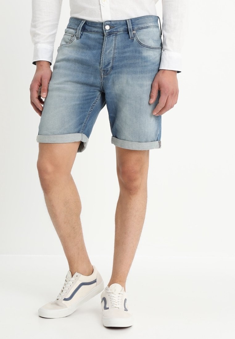 Shorts in denimazzurro chiaro con orli risvoltati, cinque tasche e chiusura con bottone. Abbinati a sneakers bianche con dettagli blu.