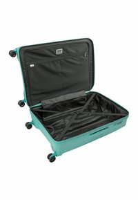 Valigia rigida verde con interno nero. Le caratteristiche includono una tasca con zip, cinturini regolabili e quattro ruote nere per la mobilità.