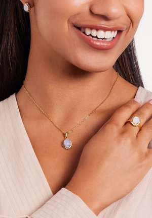 Goldschmuckset bestehend aus einer Halskette mit Anhänger und einem Ring, der einen ovalen Opal als Mittelpunkt hat, umgeben von einem strukturierten Rahmen.
