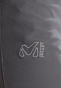 Tmavě šedá tkanina s hladkým povrchem, na boku se nachází bílá vyšívaná značka s nápisem "Millet". Jednoduchý design bez dalších vzorů.