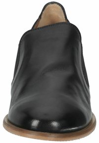 Chaussure noire en cuir à enfiler avec une surface lisse, un bout arrondi et une semelle basse beige. Présente un design minimaliste sans lacets ni embellissements.