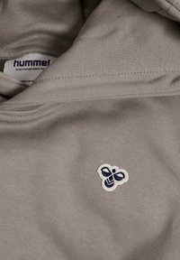 Szara bluza z gładką fakturą i małym haftowanym emblemam pszczółki w granatowym kolorze, umieszczonym w pobliżu dekoltu.