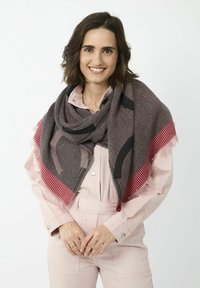 Écharpe tissée avec un motif géométrique en noir et rouge, ornée de franges. Texture douce, forme rectangulaire, drapée élégamment sur les épaules.