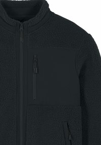 Veste en polaire gris foncé avec un col montant, une fermeture éclair sur le devant et deux poches zippées ; couche extérieure texturée et accents en tissu lisse.