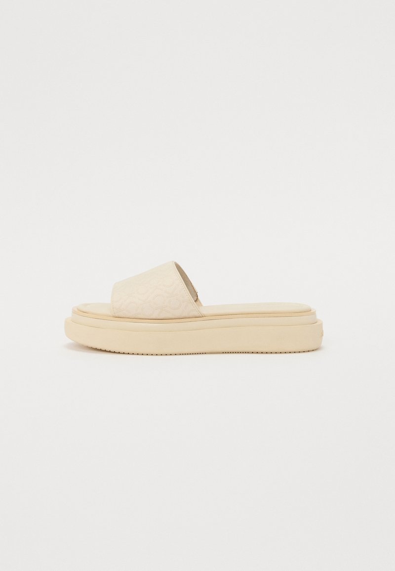 Beige platvormliugja sandaal, mille peal on reljeefne muster, lai rihm ja tekstuuriga tald. Sile materjal, ümar varvas ja kõrgendatud disain.