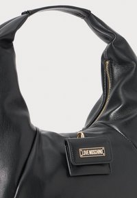 Black leather handbag with a curved handle, featuring a gold zipper and a small tag displaying the brand name "LOVE MOSCHINO."