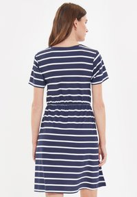 Marineblauw en witte gestreepte jurk met korte mouwen, een elastische taille en een comfortabele pasvorm. Zachte stof, knielange uitvoering en ronde halslijn.