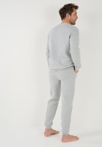 Conjunto de loungewear gris de punto que incluye una camiseta de manga larga y pantalones ajustados, ambos con puños acanalados y un acabado texturizado.