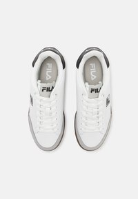 White athletic shoes with a smooth upper, lace closure, gray accents, and a dark heel. Features a logo on the tongue and side.