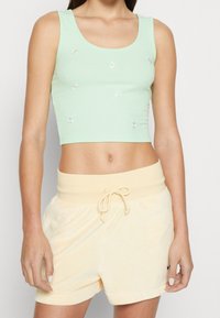 Top corto a coste verde menta con ricami floreali, abbinato a pantaloni corti in spugna gialla morbida con vita elastica regolabile.