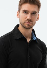 Camicia nera con colletto blu chiaro, chiusura a bottoni e una texture liscia. Progettata con una silhouette aderente.