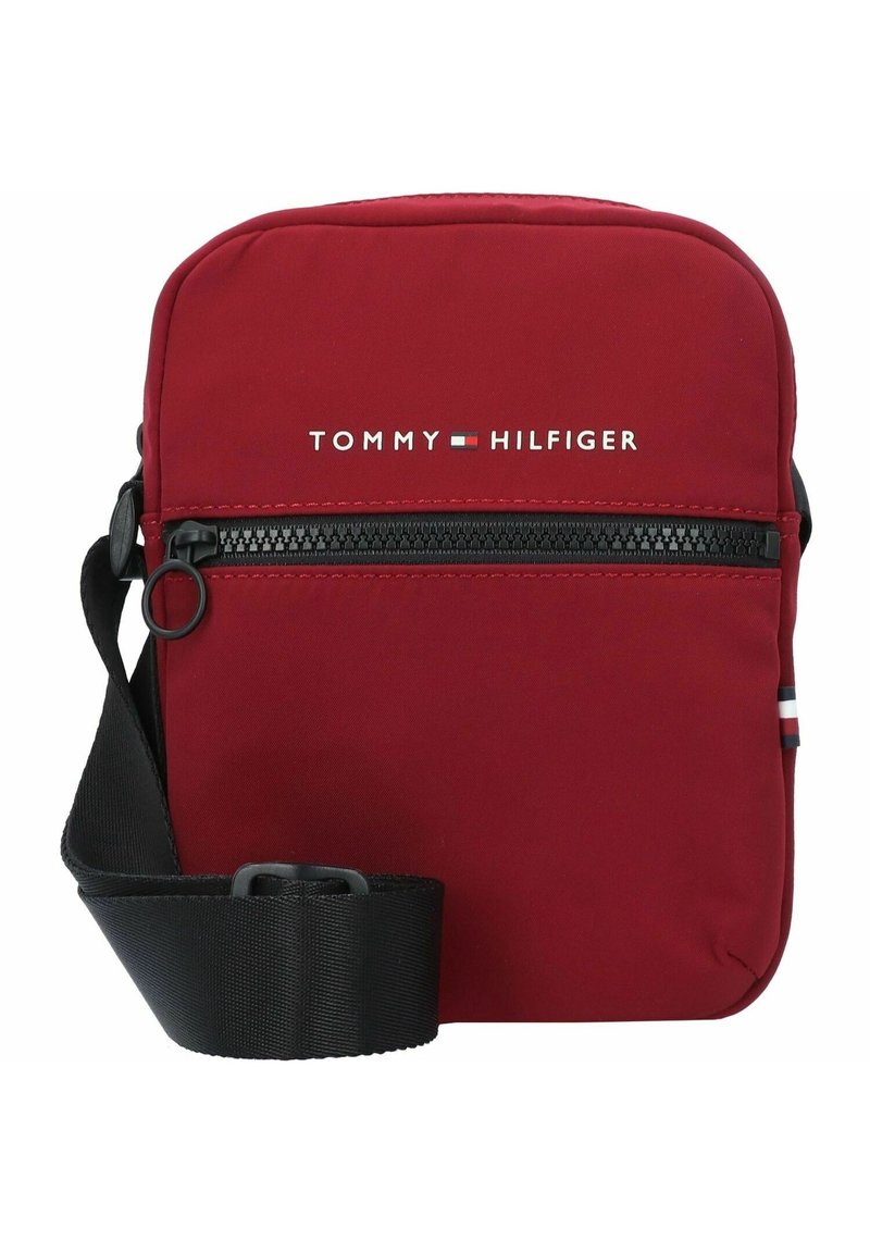 Borsetta a tracolla rossa in nylon con chiusura a zip. Presenta una tracolla nera regolabile e il logo bianco "TOMMY HILFIGER" sul fronte.