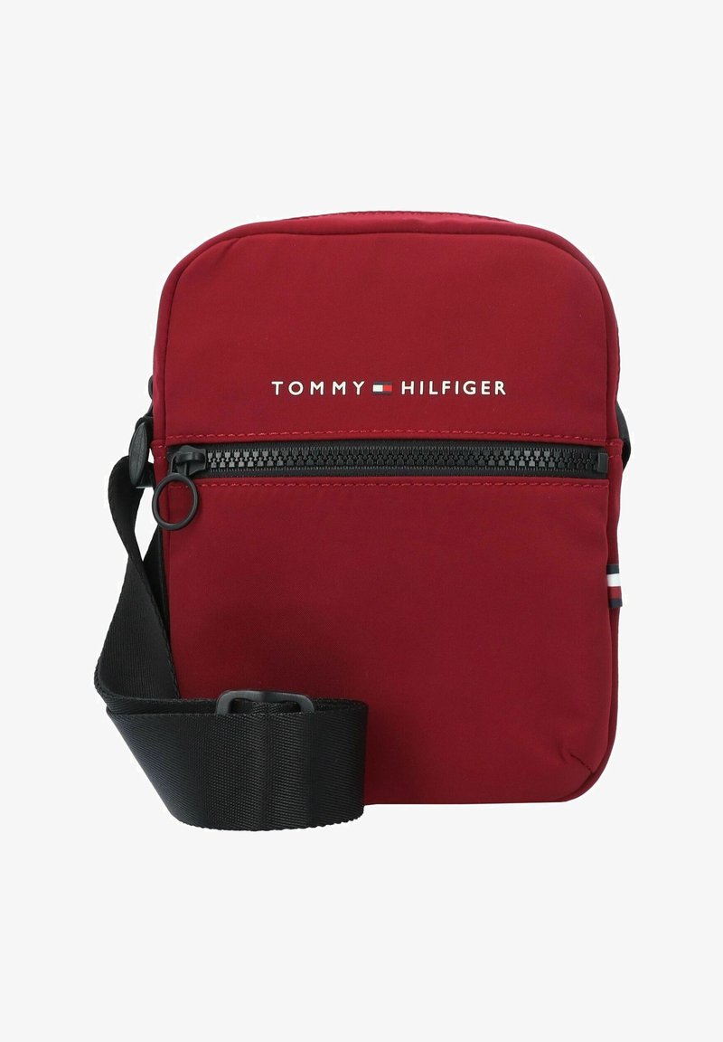 Borsetta a tracolla rossa in nylon con chiusura a zip. Presenta una tracolla nera regolabile e il logo bianco "TOMMY HILFIGER" sul fronte.